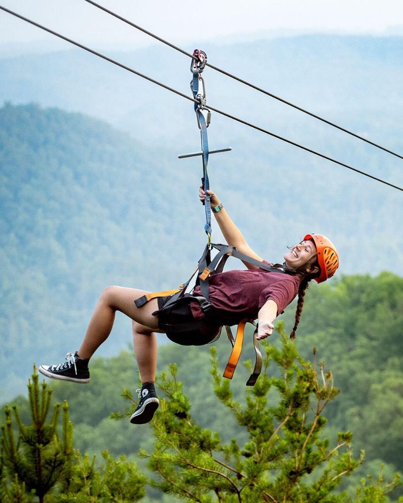 Guest ziplining over valley at Bande Falls and Resort